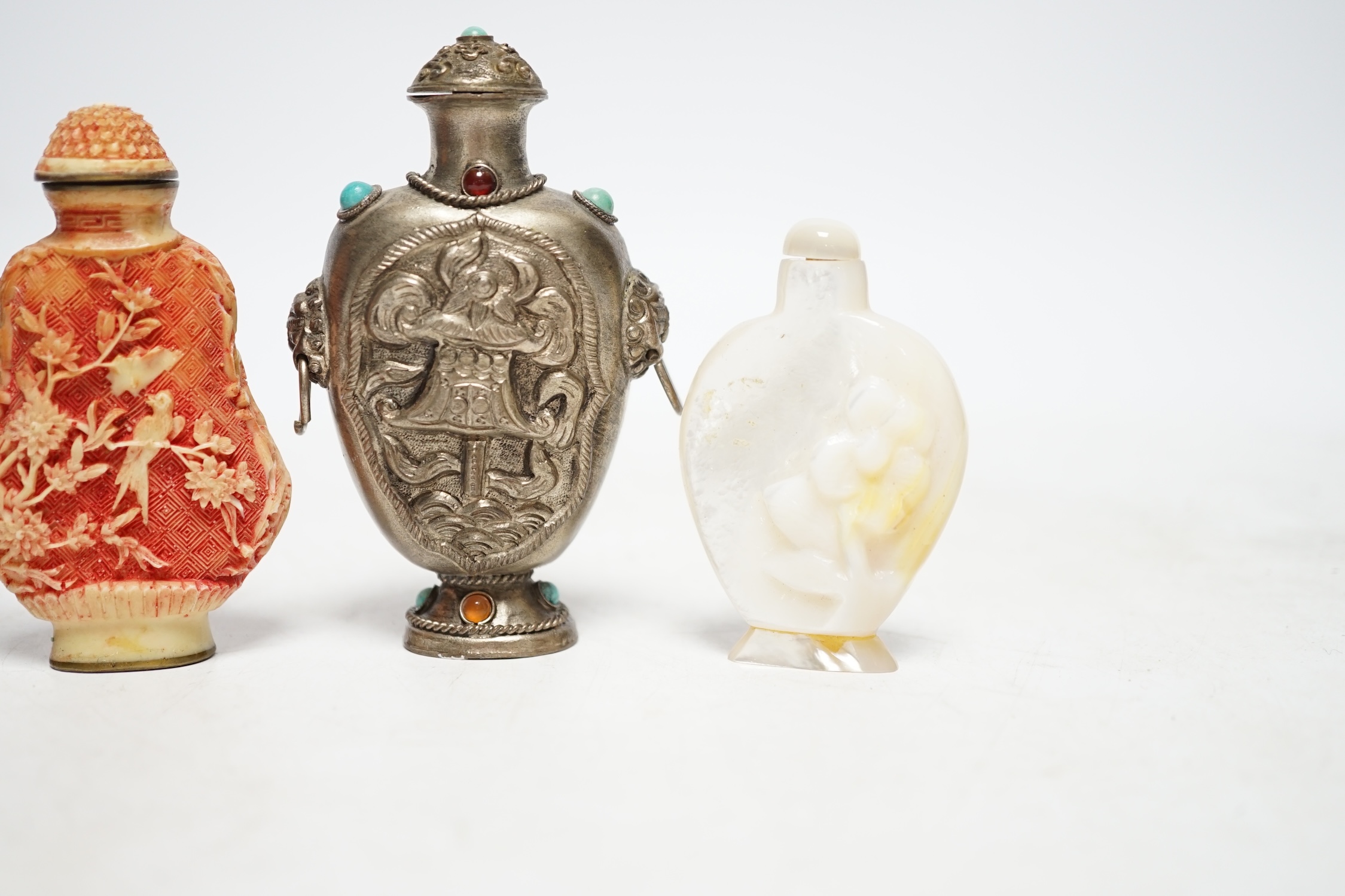 A Chinese cloisonné enamel snuff bottle, two resin snuff bottles, a carved mother of pearl snuff bottle and a Tibetan style metal snuff bottle, largest 8.5cm high